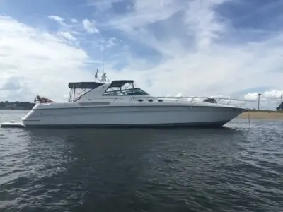 1993 Sea Ray 63 Super Sun Sport “Precious Cargo”: profile of express cruiser at anchor in calm water, guest relaxing on the aft sunpad