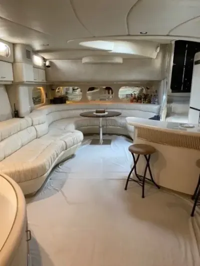 1993 Sea Ray 63 Super Sun Sport “Precious Cargo”: salon with curved cream leather sectional, round pedestal table and bar counter with stools