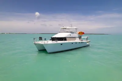 2002 Wright/Lavranos 50 Power Catamaran “Peace”: twin-hulled power catamaran at anchor in shallow turquoise water, bow-quarter view