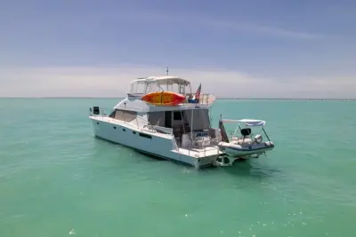 2002 Wright/Lavranos 50 Power Catamaran “Peace”: stern-quarter view of power catamaran with tender on davits and kayaks on flybridge rail