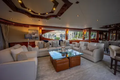 2004 Lazzara 106 Motor Yacht “Passion”: salon lounge with cream sofas and armchairs around a glass table over leather ottomans