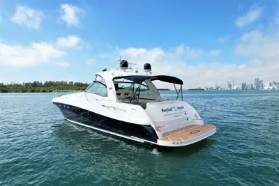 2005 Sea Ray 50 Sundancer “Nautical Dreamer”: stern-quarter view of navy-hulled express cruiser with teak-style swim platform and cockpit bimini