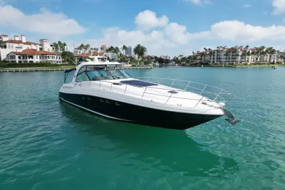 2005 Sea Ray 50 Sundancer “Nautical Dreamer”: bow-quarter view of navy-hulled express cruiser at anchor with foredeck sunpad and bow rail