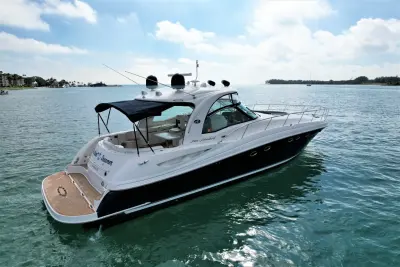 2005 Sea Ray 50 Sundancer “Nautical Dreamer”: elevated stern-quarter view showing teak-style swim platform, cockpit table and navy bimini top