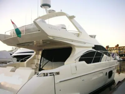 2006 Azimut 55 Flybridge: stern-quarter view of docked ivory flybridge yacht with radar arch and cockpit canvas