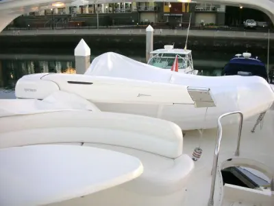 2006 Azimut 55 Flybridge: flybridge with covered tender on davit crane, white curved settee and table