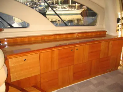 2006 Azimut 55 Flybridge: salon sideboard of high-gloss cherry cabinetry beneath curved hull-side windows