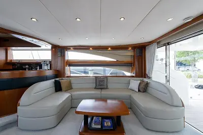 2009 Princess 70 Flybridge “Social Services”: grey leather U-shaped salon settee around a cherry coffee table beside open aft doors