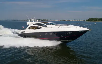 2010 Sunseeker 64 Predator “Bella”: sport yacht at speed with navy hull, red stripe and long foredeck with bow rail