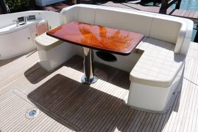 2013 Azimut 64 Flybridge “Vivere”: cockpit dining area with U-shaped cream settee and high-gloss wood table on teak deck
