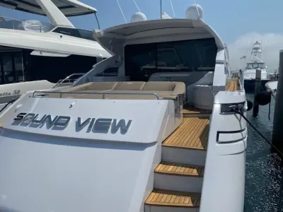 2013 Pershing 64 “Sound View”: stern-quarter view at dock showing teak side steps, beige sunpad and tinted cockpit glass