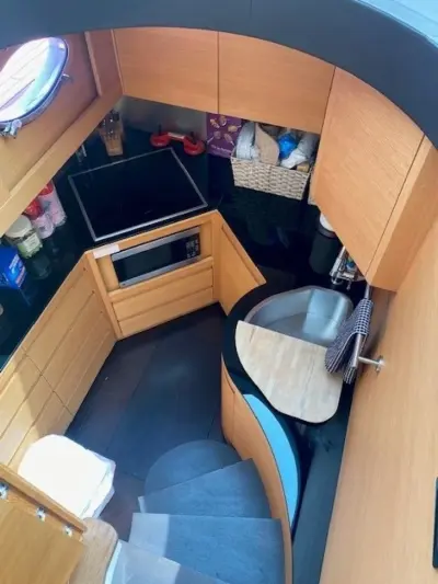 2013 Pershing 64 “Sound View”: overhead view of galley with oak cabinets, black counters, induction cooktop and curved stairs