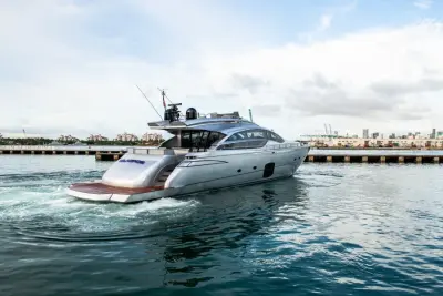 2013 Pershing 82 “Milagros”: stern-quarter view of silver sport yacht pulling away, teak swim platform and open cockpit