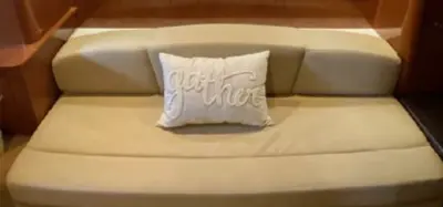 2014 Sea Ray Sundancer 33 “Peace of Mind”: beige cabin settee with embroidered throw pillow against cherry-wood paneling