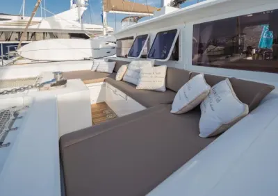 2017 Lagoon 450: forward cockpit lounge with taupe cushions and white throw pillows below cabin windows