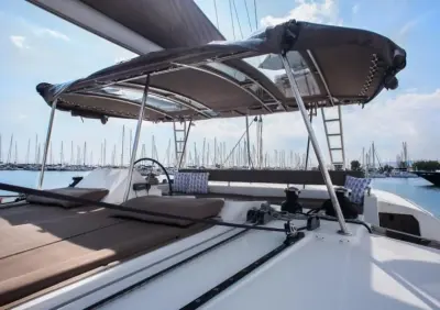 2017 Lagoon 450: flybridge with helm wheel, sunbeds and winches under a grey canvas bimini