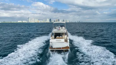 2021 Ferretti Yachts 550 “Haven”: stern view underway showing covered tender on teak swim platform and open cockpit
