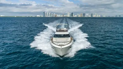 2021 Ferretti Yachts 550 “Haven”: head-on running shot of flybridge yacht with bow sunpad and wide wake behind