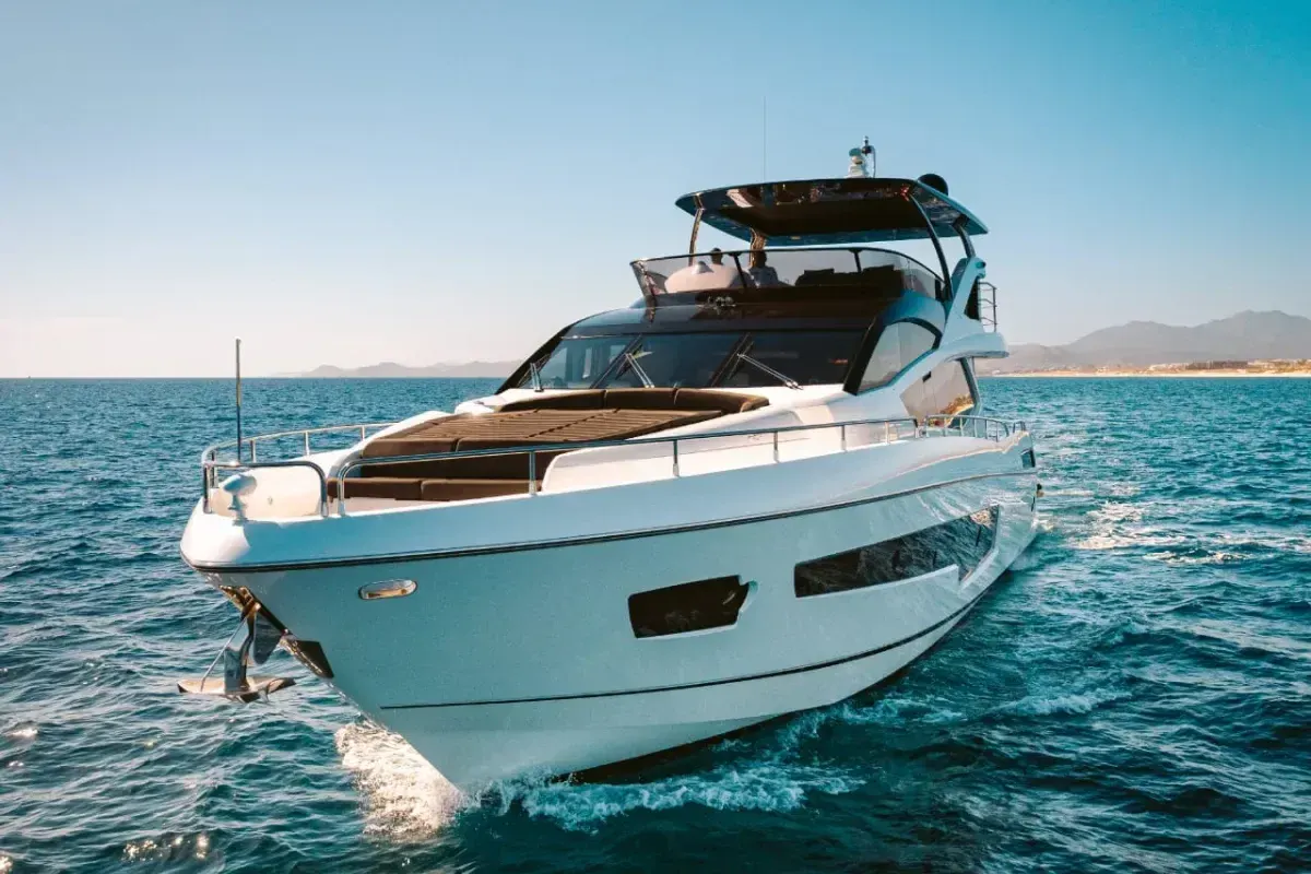 A white flybridge motor yacht running at speed across open blue water
