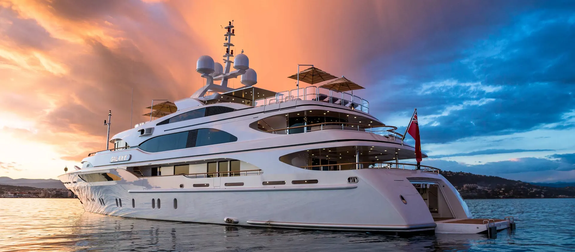 A large multi-deck motor yacht at anchor at sunset